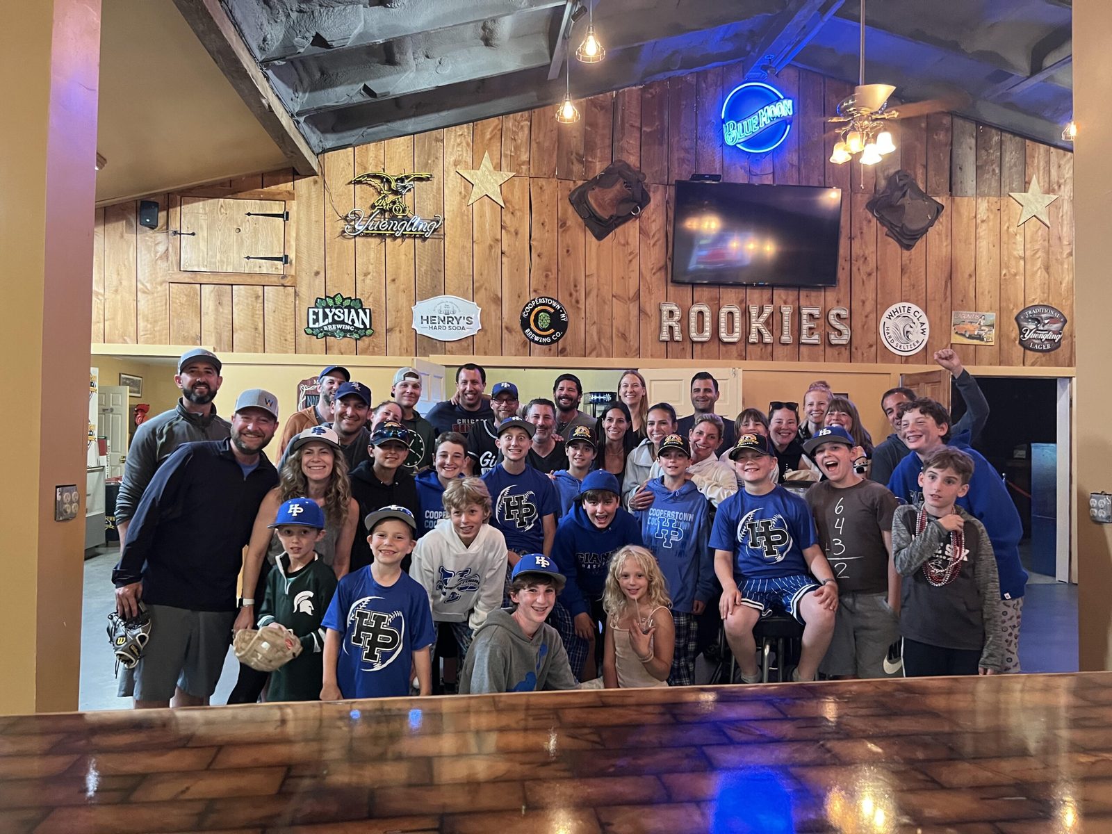 A youth baseball team with parents and siblings gathered for a team party inside the Clubhouse