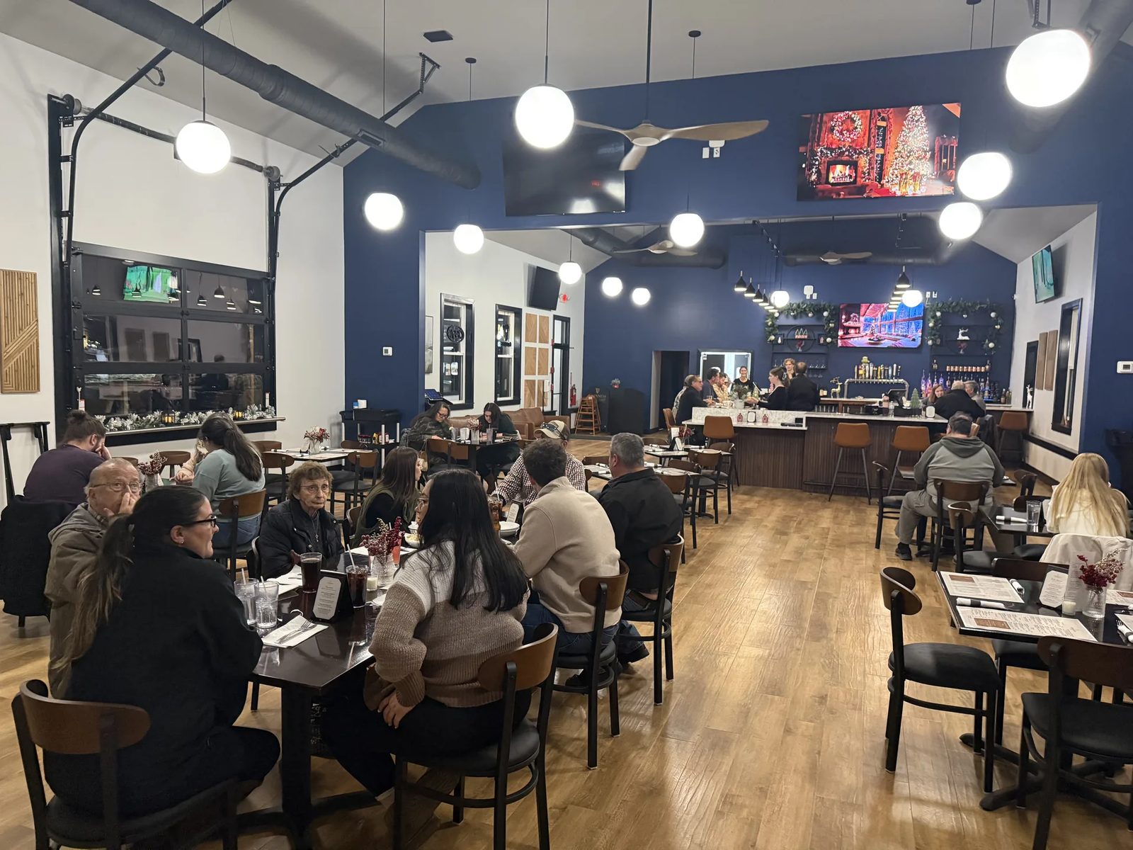 A full evening dining room at Fenimore's Table, with families and groups at tables under globe pendant lights